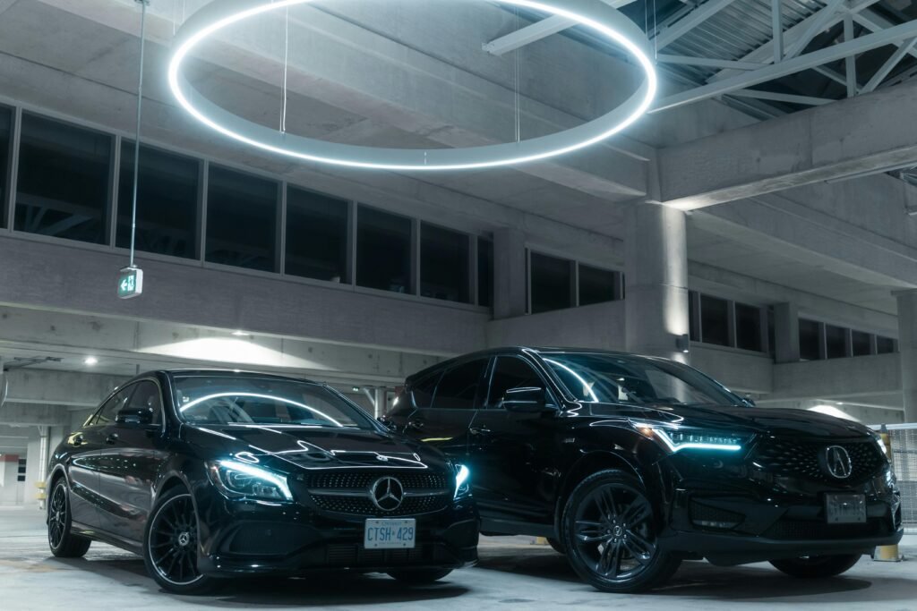 pexels-photo-13578691-13578691 Two luxury cars, a Mercedes and an Acura, parked in an illuminated modern garage.